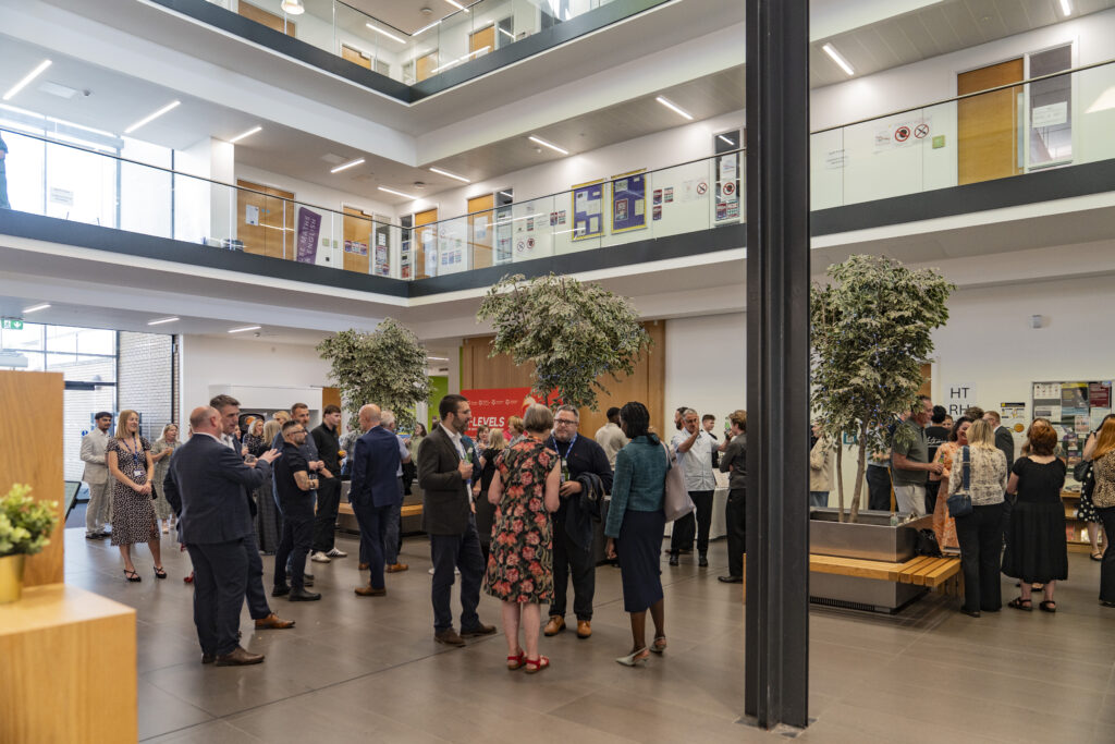 A spacious, modern interior filled with people mingling and conversing.